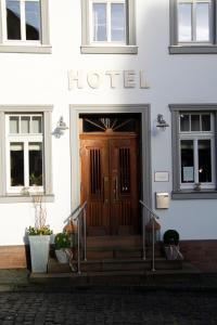 una puerta delantera de un edificio con escaleras y plantas en Zur Ewigen Lampe Romantisches Landhotel & Restaurant en Nideggen