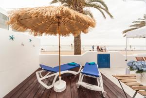 twee stoelen en een parasol op een terras met het strand bij Luxury Suite Sea Front III in Playa Honda