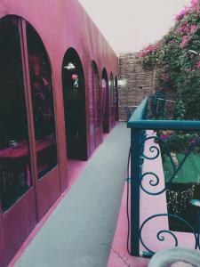 a pink building with a blue railing and flowers at Riad Le Lieu in Tiznit