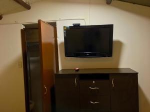 a flat screen tv on a wall next to a refrigerator at Villa Suite Emanuel in Bogotá