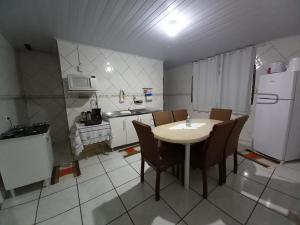 Sobrado 02 quartos próx. Hotel Recanto Cataratas في فوز دو إيغواسو: مطبخ مع طاولة وكراسي وثلاجة