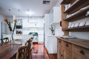 a kitchen with white cabinets and a wooden table at Wattle Terrace in Castlemaine