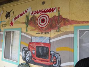 
a red truck parked in front of a wall with graffiti on it at El Trovatore Motel in Kingman
