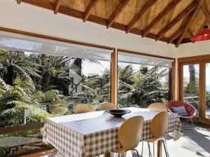 a dining room with a table and chairs on a patio at Amidst Bush and Birdsong - Pukawa Holiday Home in Kuratau