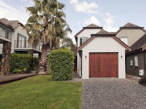 a house with a garage with a palm tree at Putt it at Pauanui - Pauanui Holiday Home in Pauanui