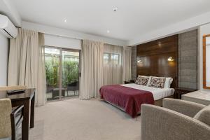 ein Hotelzimmer mit einem Bett, einem Tisch und Stühlen in der Unterkunft Boulcott Lodge in Lower Hutt