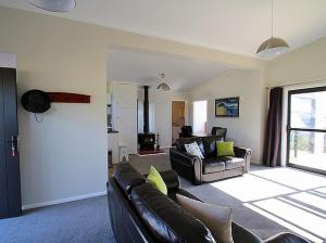 sala de estar con 2 sofás y chimenea en Ponderosa - Waitarere Beach Bach, en Waitarere