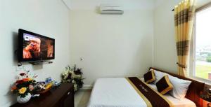 a bedroom with a bed and a tv on the wall at Đào Hùng Hotel in Lao Bao