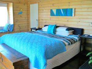 a bedroom with a bed with a blue comforter at Paradise in Flaxmill Bay - Flaxmill Bay Home in Cooks Beach
