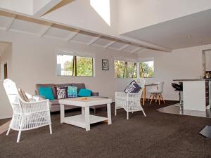 a living room with white chairs and a couch at Beach Central - Whangamata Holiday Home in Whangamata