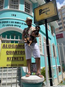 a man standing on a statue holding a dog at Porto das Palmeiras Hostel in Salvador