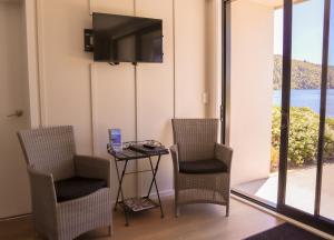 Zimmer mit 2 Stühlen und einem Tisch mit einem TV in der Unterkunft Braxmere Lodge in Turangi