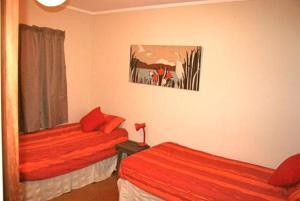 a bedroom with two beds with red sheets at Nestled Atop the Lane - Pukawa Bay Holiday Home in Kuratau