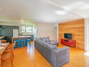 a living room with a gray couch and a kitchen at Key to Whangapoua - Whangapoua Holiday Home in Whangapoua