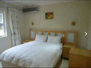 Un dormitorio con una gran cama blanca y una ventana en Caribbean Estates: Barbados No. 12, en Port Edward