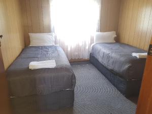 two beds in a small room with a window at Limestone Coast Tourist Park in Mount Gambier