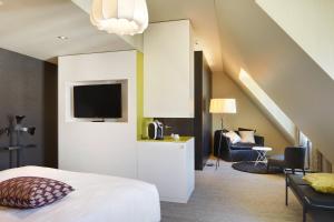 Schlafzimmer mit einem Bett, einem TV und einem Stuhl in der Unterkunft Continental Park in Luzern