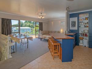 a kitchen and living room with a table and a couch at Bach on Boulevard - Pauanui Holiday Home in Pauanui