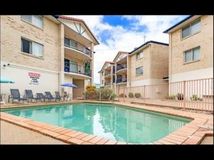 a swimming pool in front of two apartment buildings at Sandy Toes in Bellara