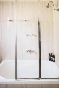 a shower with glass doors and a tub at Station Master's House in Castlemaine