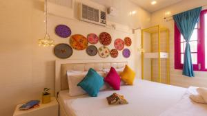 a bedroom with a bed with colorful pillows and plates on the wall at Madpackers Amritsar in Amritsar