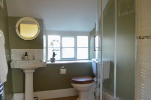 a bathroom with a toilet and a sink and a window at Darly Cottage in Bourton on the Water
