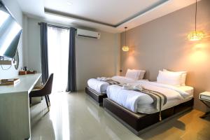 Un dormitorio con dos camas y un escritorio y un televisor. en Worachat Boutique Hotel, en Phetchabun