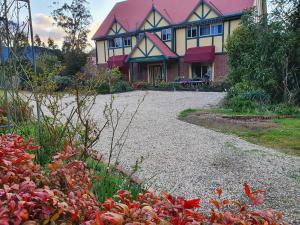 Oaktree Guest House في Narbethong: منزل به سقف وردي وممر حصى
