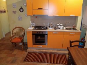 an orange kitchen with a stove and a sink at GRAZIOSO Appartamento in Spoleto
