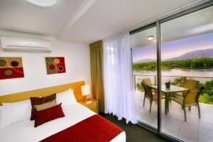 a bedroom with a bed and a balcony with a table at Edge Apartment Hotel in Rockhampton