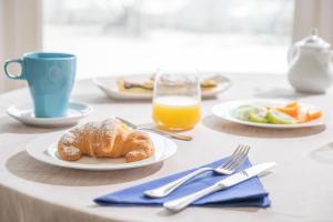 a table with plates of food and a glass of orange juice at Hotel Cavalluccio Marino in Santa Marinella
