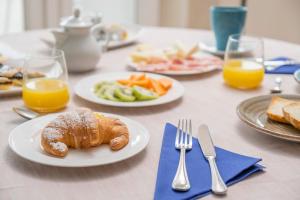 a table with plates of breakfast foods and orange juice at Hotel Cavalluccio Marino in Santa Marinella