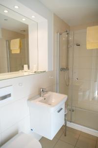 La salle de bains blanche est pourvue d'une douche et d'un lavabo. dans l'établissement Gästehaus Sonnenhof, à Cassel
