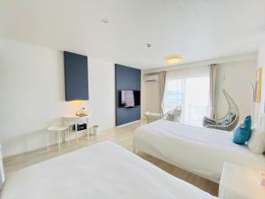 a hotel room with two beds and a window at Lalamare Kouri in Nakijin