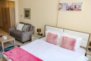 ドバイにあるSHH - Furnished Studio Apartment, Silicon Gates 4のベッドルーム1室(ピンクの枕とソファ付きのベッド1台付)