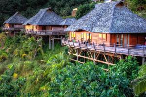 een rij houten huizen op een heuvel met bomen bij Luxurious Tropical Moorea Villa in Papetoai