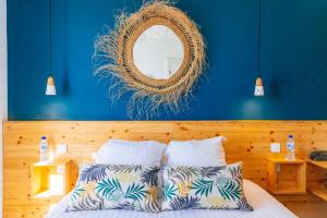 a bedroom with a blue wall with a bed and a mirror at Hôtel Café Miramar in Le Grau-du-Roi
