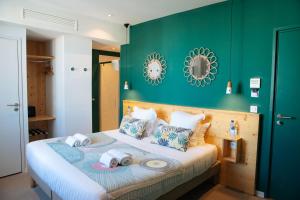 a green bedroom with a bed with towels on it at Hôtel Café Miramar in Le Grau-du-Roi