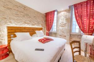 a bedroom with a large white bed with red curtains at Europe Hôtel in Castres
