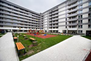 a park with benches and a playground in front of a building at Komputerowa Serviced Apartments by P&O in Warsaw