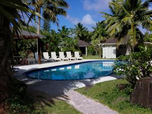 a swimming pool in a yard with chairs and palm trees at Palm Grove in Rarotonga