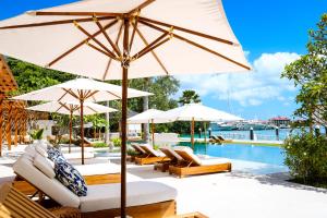L'Escale Resort Marina & Spa - Small Luxury Hotels of the World في ماهي: مسبح مع مظلات وكراسي صالة بجانب مسبح
