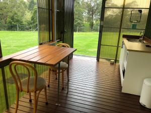 a screened in porch with a wooden table and chairs at Walsh Farm Shepherd’s Rest in Milton