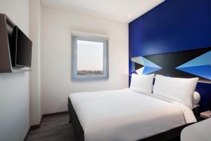 1 dormitorio con cama blanca y pared azul en MD 7 Hotel Cirebon, en Cirebon