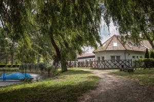 ein Haus neben einem Fluss mit einem blauen Boot in der Unterkunft Tó-Part Panzió Kőszeg in Kőszeg