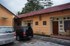 dos autos estacionados frente a una casa en QQ Guesthouse, en Kalasan