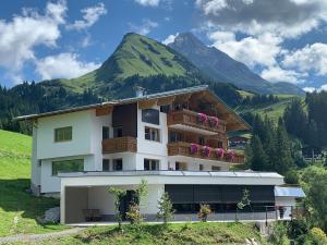 une maison sur une colline avec une montagne en arrière-plan dans l'établissement Birg 1414, à Warth am Arlberg