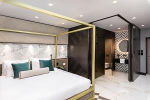 a bedroom with a canopy bed and a bathroom at Lure Hotel & Spa - Adults Only in Mellieħa
