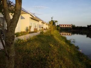 a building next to a river next to a house at homestay568 Branch 2 in Muang Suang