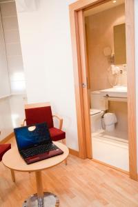 ordenador portátil en una mesa en una habitación con baño en Hostal Navarra en Pamplona